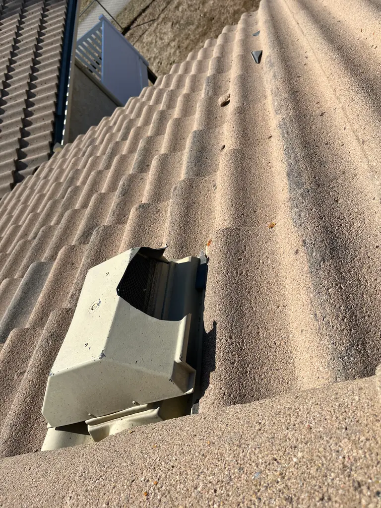 Hail-damaged roof vent on a clay tile roof in Calgary