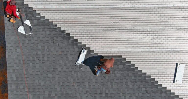 two body strapped roofers installing asphalt shingles