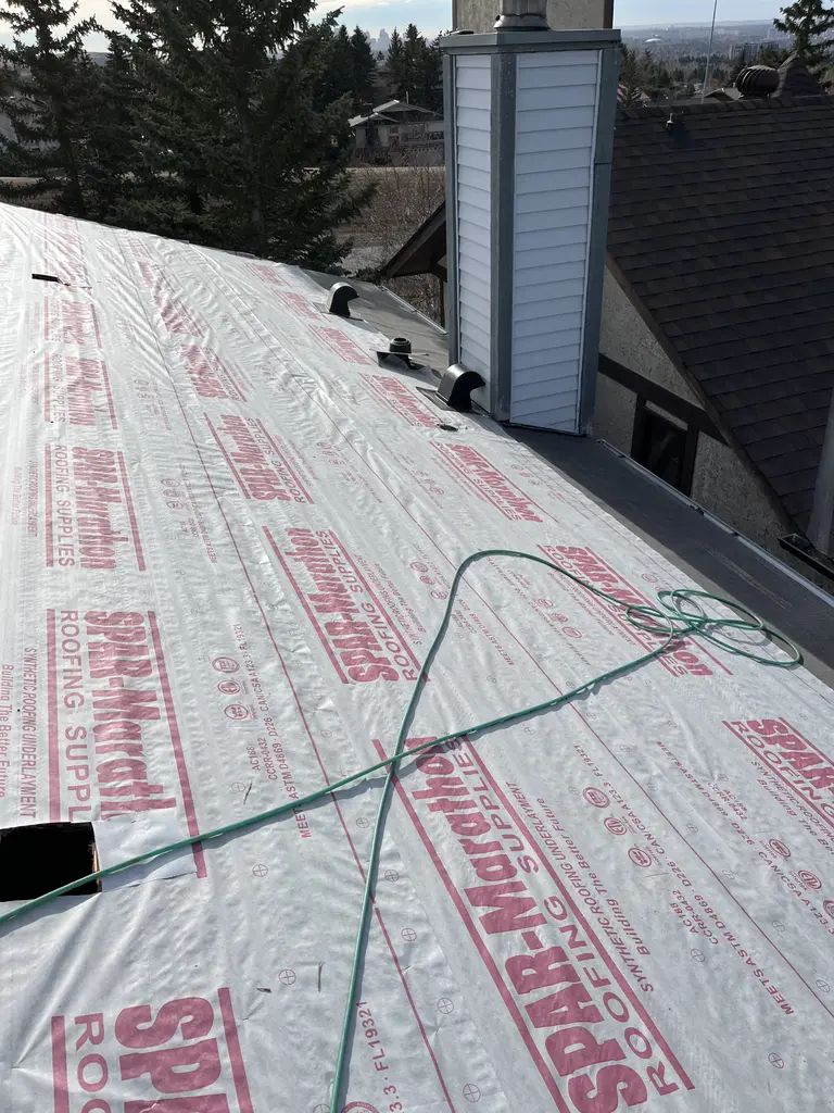 Synthetic underlayment, new chimney chase cap and chimney flashing during a Calgary shingle replacement, 2025
