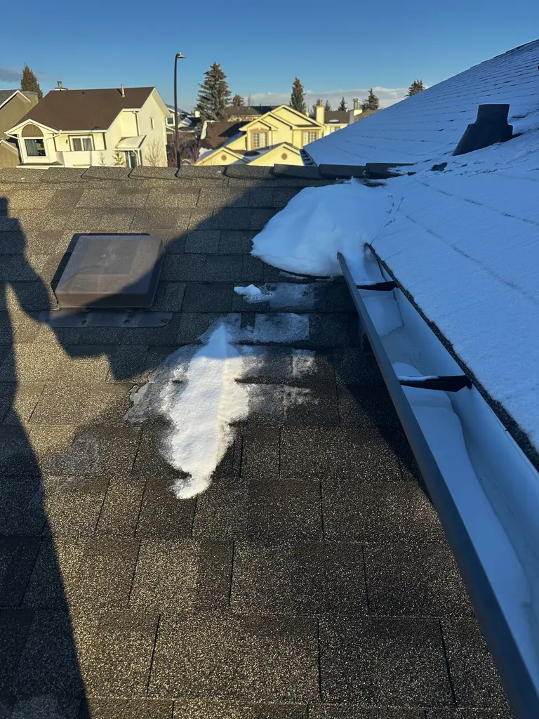 Winter roof inspection in Calgary showing ice damming along the shingles